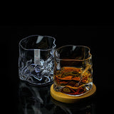 Deux verres Crumple givrés sur table, un tenu en main et un vide, texture froissée visible
