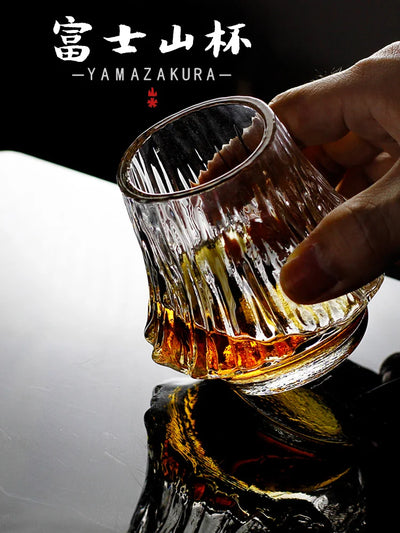 Verre Flamme du Fuji tenu en main, stries verticales et whisky ambré en gros plan